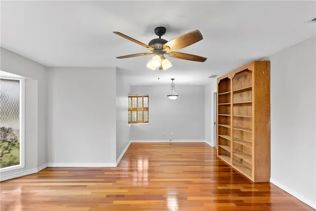 a view of an empty room with window and wooden floor