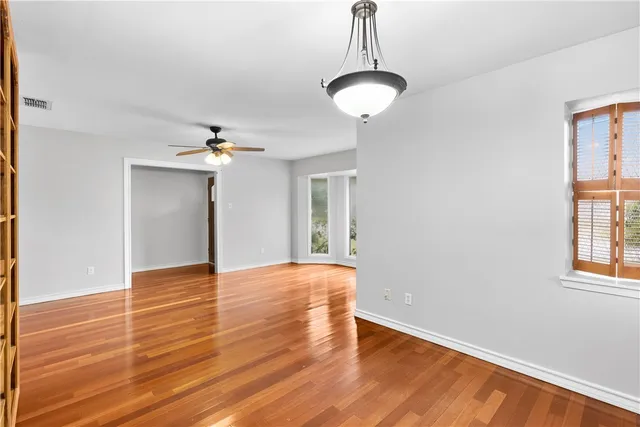 a view of an empty room with window and wooden floor