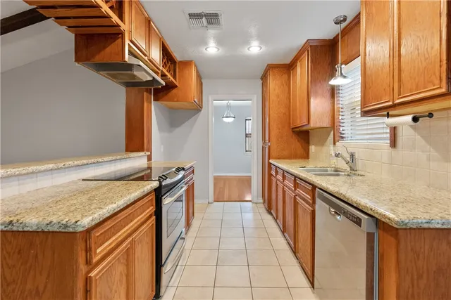 a kitchen with stainless steel appliances granite countertop a sink and a refrigerator