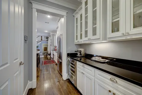 a kitchen with stainless steel appliances kitchen island granite countertop a sink dishwasher a stove a refrigerator a dining table and chairs with wooden floor