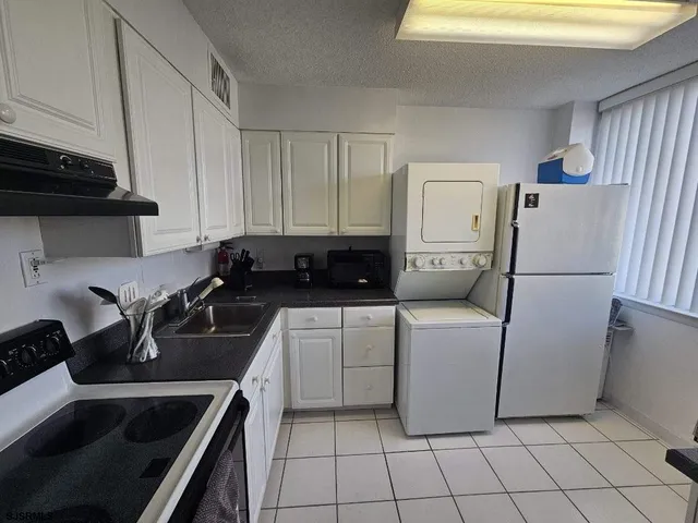 a kitchen with stainless steel appliances granite countertop a refrigerator sink and white cabinets