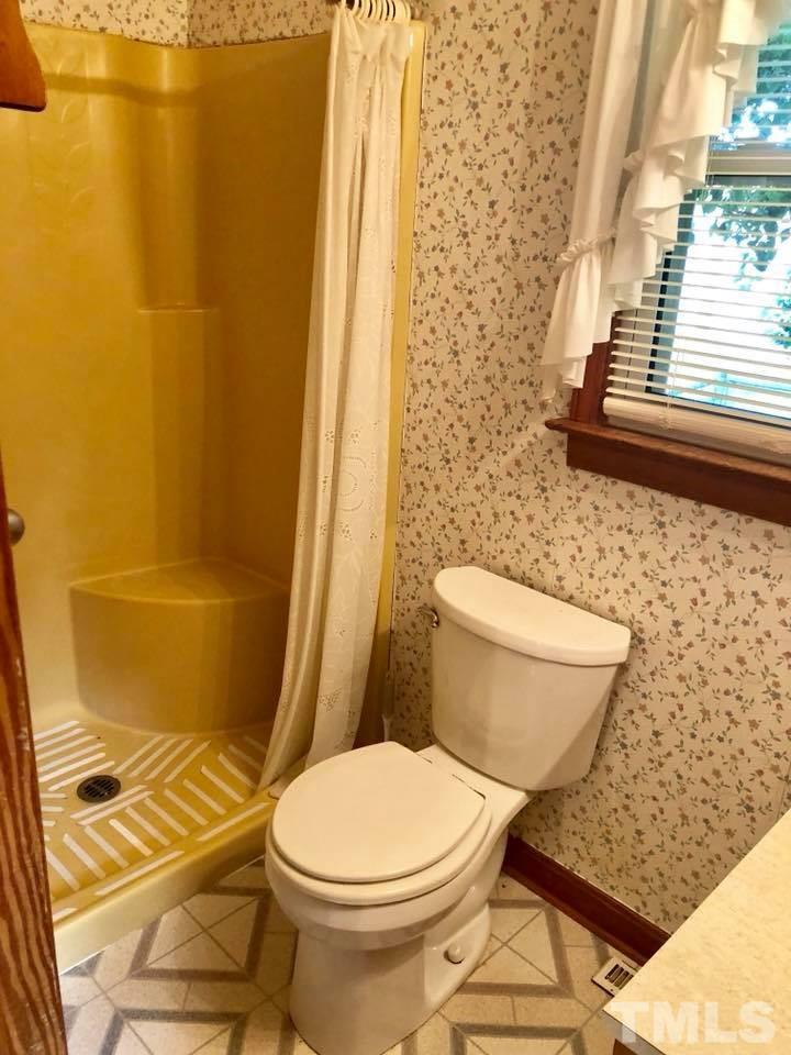 2604 Burlington Road Roxboro, NC 27574 - Photo 14 of 17 a white toilet sitting next to a shower curtain