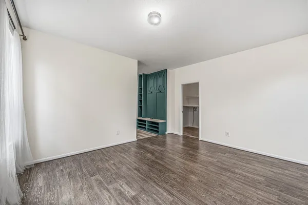 a view of an empty room with wooden floor and a window