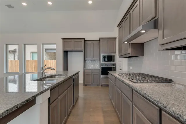 a kitchen with stainless steel appliances granite countertop a sink stove and refrigerator