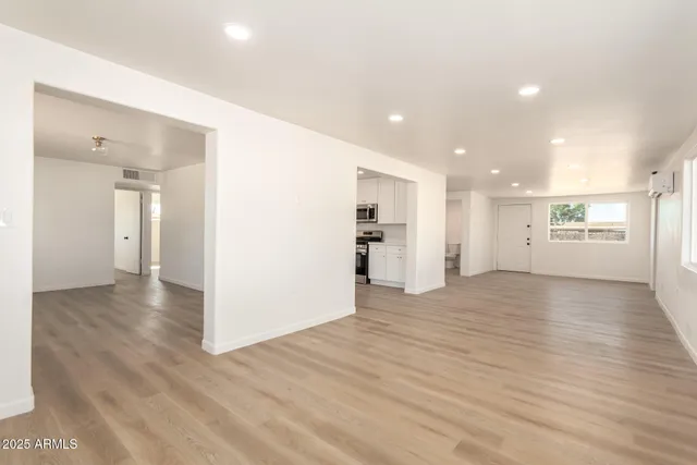 a view of an empty room with window and wooden floor