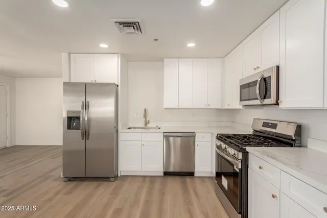 a kitchen with white cabinets stainless steel appliances and sink