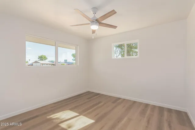 an empty room with wooden floor and ceiling fan