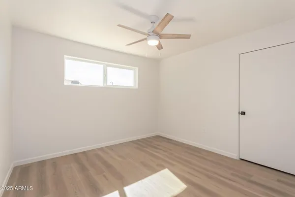 an empty room with wooden floor and fan