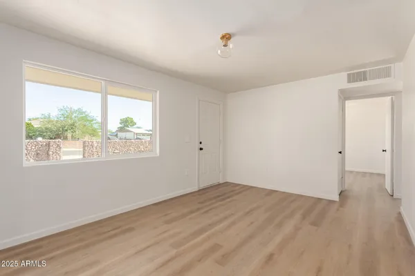 an empty room with wooden floor and windows