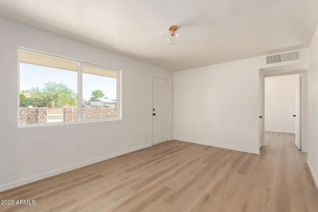 an empty room with wooden floor and windows