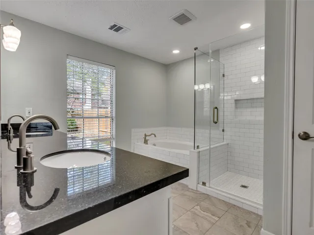 a bathroom with a granite countertop sink mirror bathtub and shower