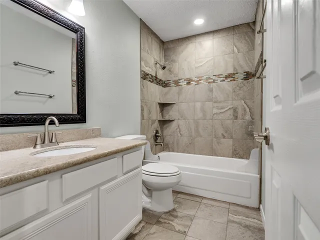 a bathroom with a granite countertop sink a toilet and shower