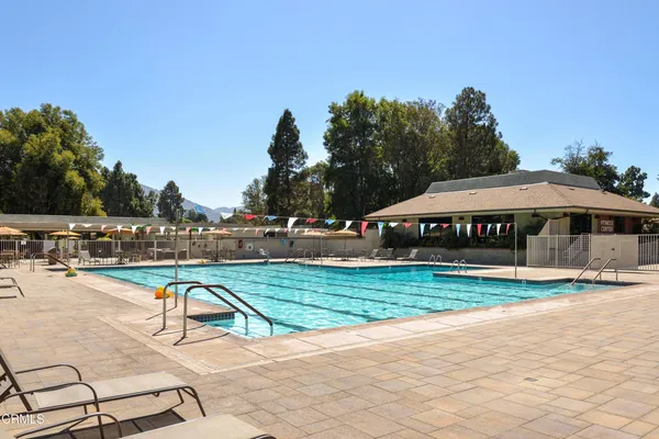 a view of swimming pool with outdoor seating and trees in the background
