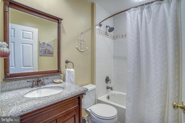 a bathroom with a granite countertop sink toilet a mirror and shower