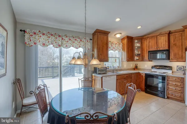 a kitchen with granite countertop a stove a sink a dining table and chairs