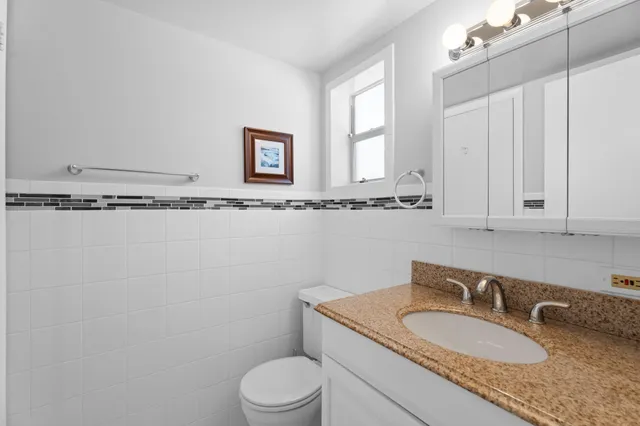 a bathroom with a granite countertop toilet sink and mirror