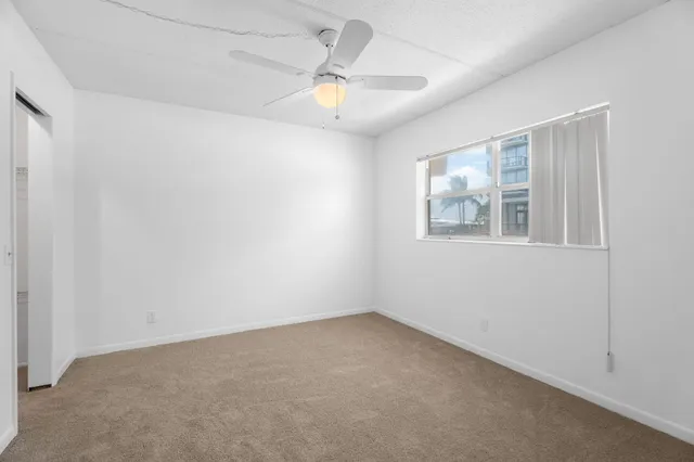 en empty room with windows and ceiling fan