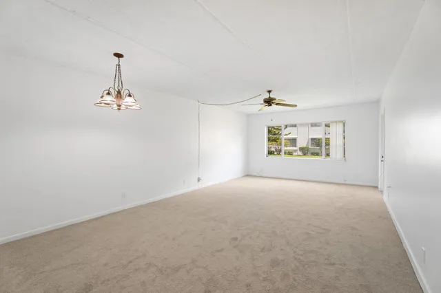 an empty room with windows and ceiling fan