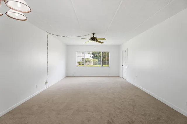 an empty room with windows and ceiling fan