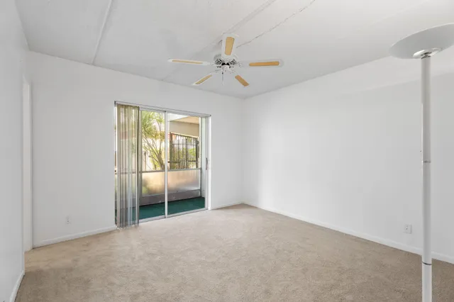 an empty room with a ceiling fan and a window