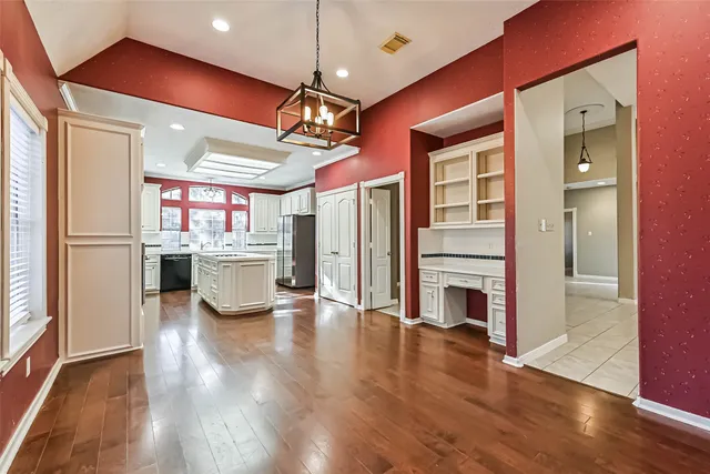 a kitchen with stainless steel appliances kitchen island granite countertop a refrigerator a oven a stove and a wooden floors