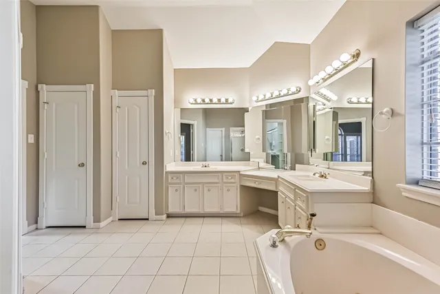 a bathroom with a tub a sink and mirror
