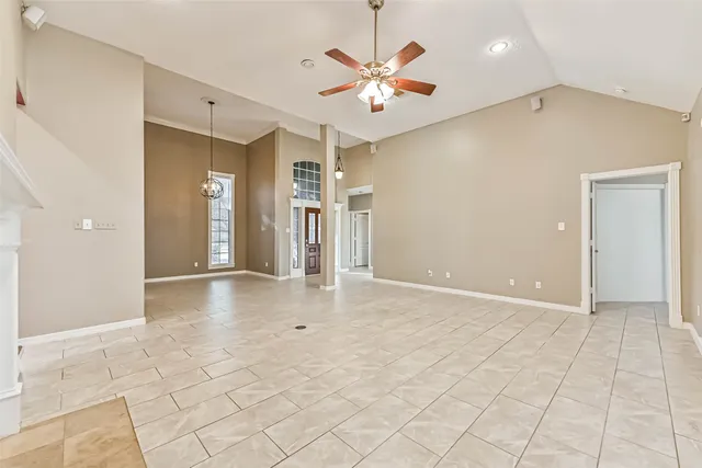 an empty room with fan and a chandelier fan