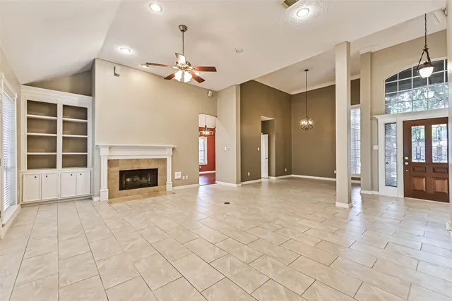 a view of an empty room with a fireplace and a chandelier fan