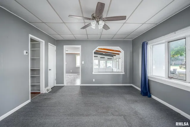 an empty room with windows and chandelier fan