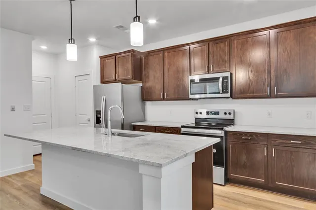 a kitchen with stainless steel appliances a sink a stove a refrigerator cabinets and a counter top space