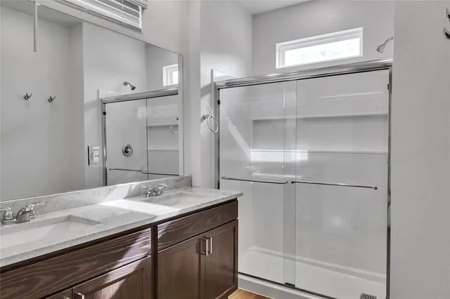 a bathroom with a granite countertop shower sink and mirror