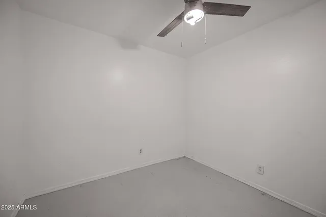 an empty room with a ceiling fan and window