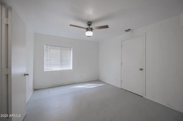 an empty room with a window and ceiling fan