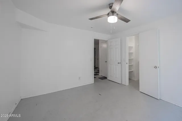 an empty room with a ceiling fan and a window