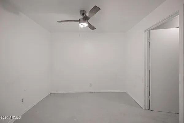 an empty room with a ceiling fan and mirror