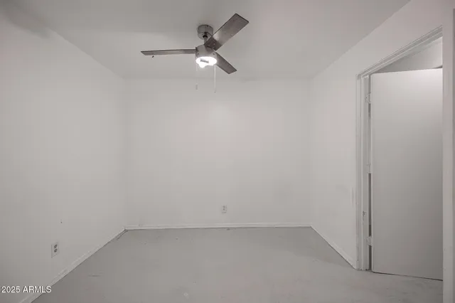 an empty room with a ceiling fan and mirror