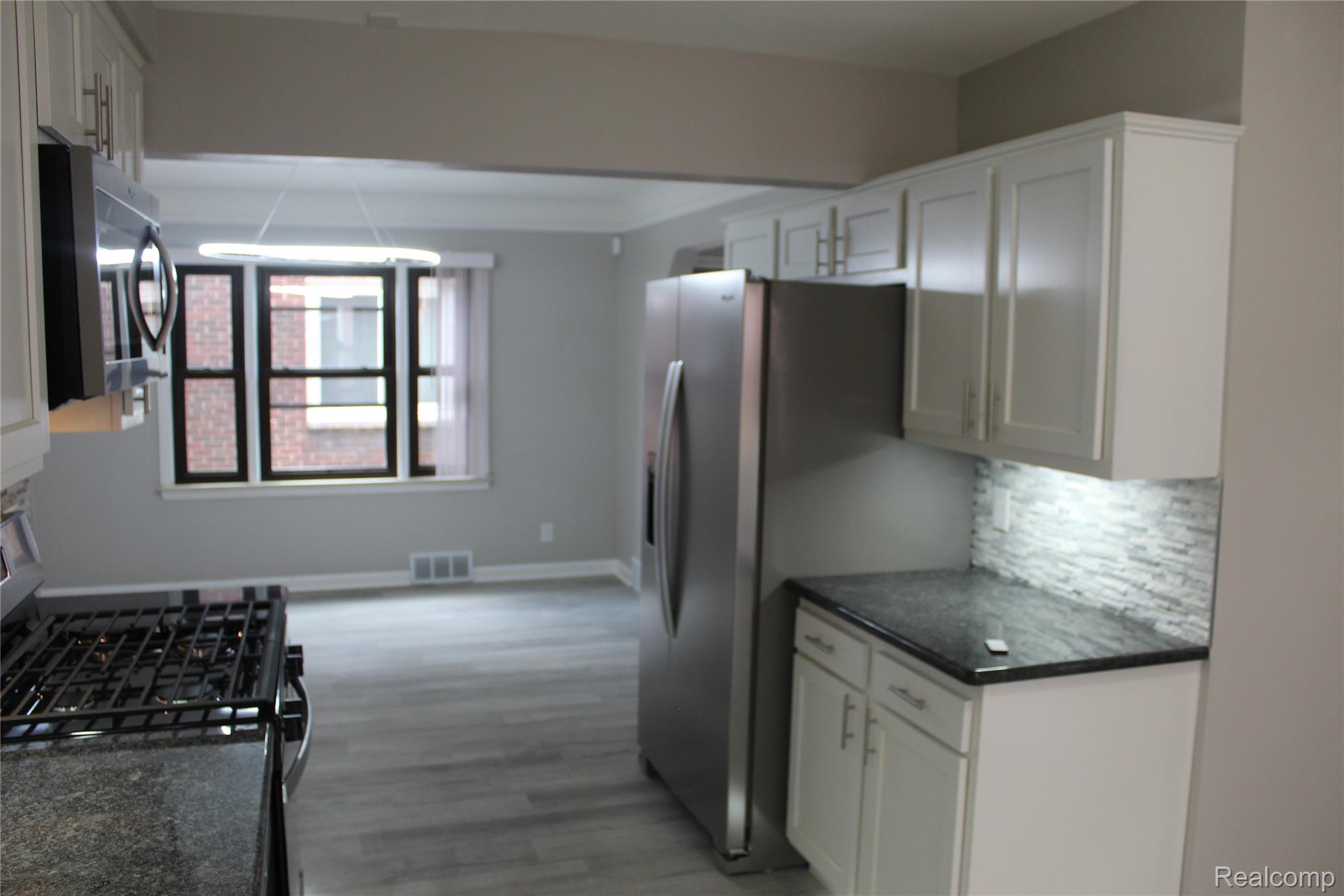 5543 Balfour Road Detroit, MI 48224 - Photo 7 of 54 Kitchen with white shaker cabinetry, stainless steel appliances, dark stone countertops, and a stacked tile backsplash