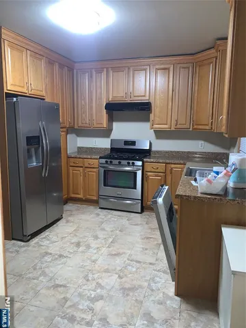 a kitchen with granite countertop a refrigerator and a stove top oven