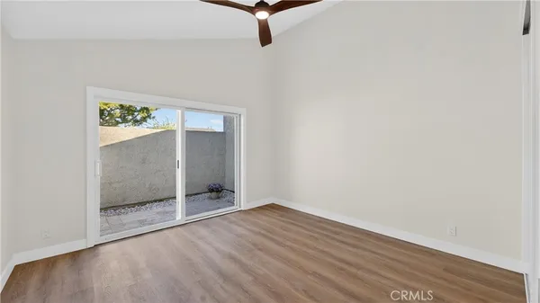 a view of an empty room with wooden floor and a bathroom