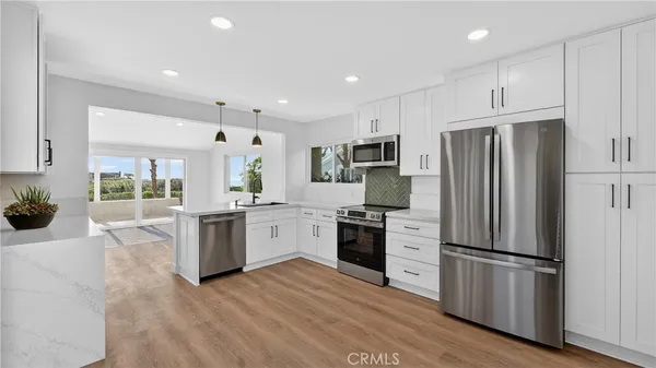 a kitchen with a refrigerator stove and wooden floor