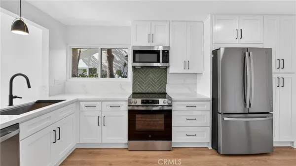 a kitchen with white cabinets and stainless steel appliances