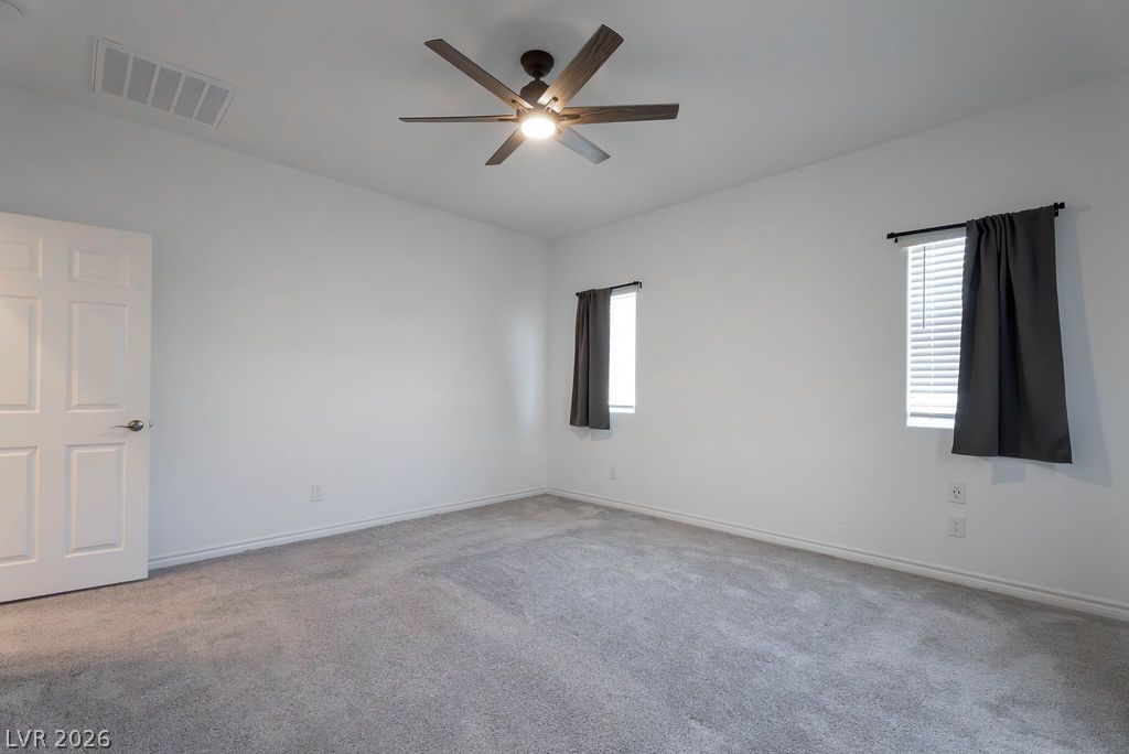 7126 Calvert Cliffs Street North Las Vegas, NV 89084 - Photo 23 of 44 A quiet bedroom featuring plush carpeting, generous windows, and a functional ceiling fan.