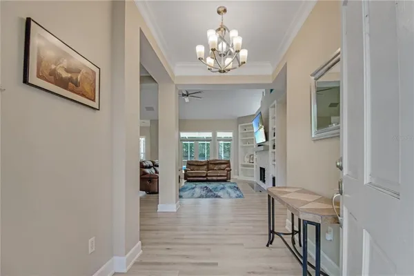 a view of a hallway with wooden floor and a chandelier