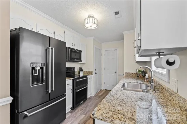 a kitchen with stainless steel appliances granite countertop a refrigerator a stove and a sink with wooden floor