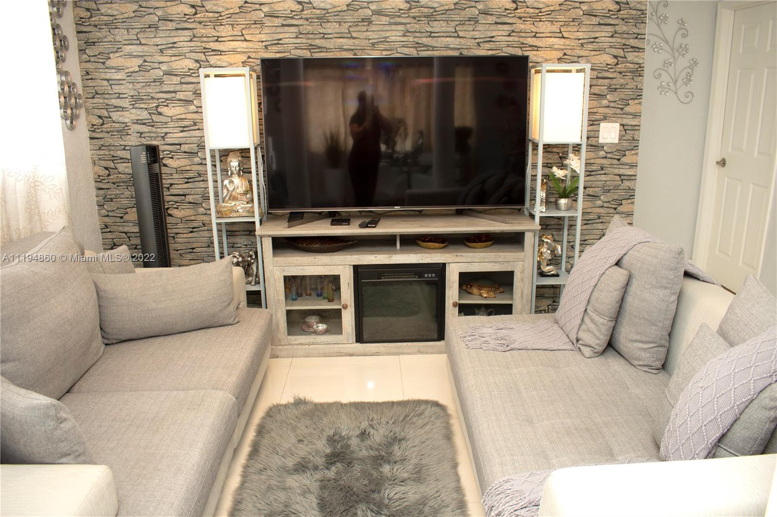 398 East 56th Street Hialeah, FL 33013 - Photo 8 of 30 a living room with a flat screen tv a fireplace and a flat screen tv