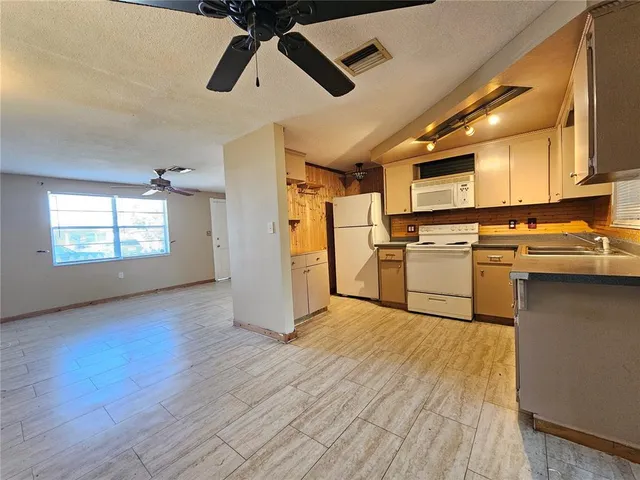 a kitchen with stainless steel appliances granite countertop a refrigerator a stove top oven a chimney wooden floor and cabinets