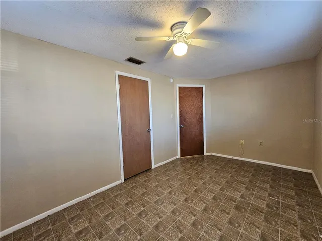 an empty room with a chandelier fan and a table