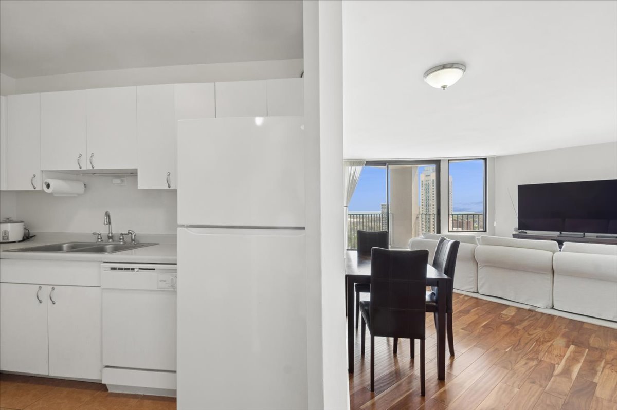 5320 North Sheridan Road, Unit 2403 Chicago, IL 60640 - Photo 4 of 18 a kitchen with stainless steel appliances granite countertop a refrigerator a stove a dining table and chairs with wooden floor