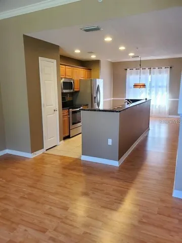 a living room with stainless steel appliances kitchen island granite countertop a large counter top and wooden floors