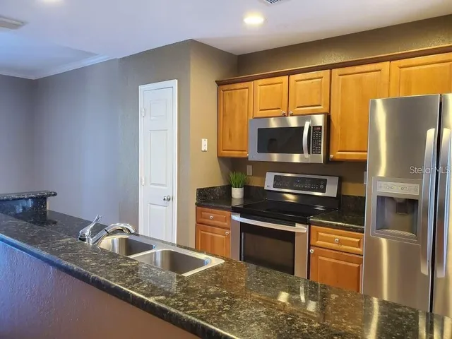 a kitchen with granite countertop a refrigerator stove and sink